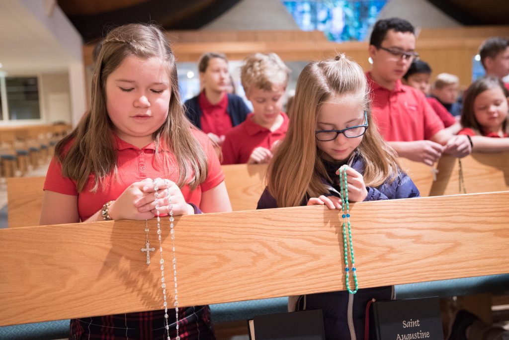 students knelt in pews praying rosary