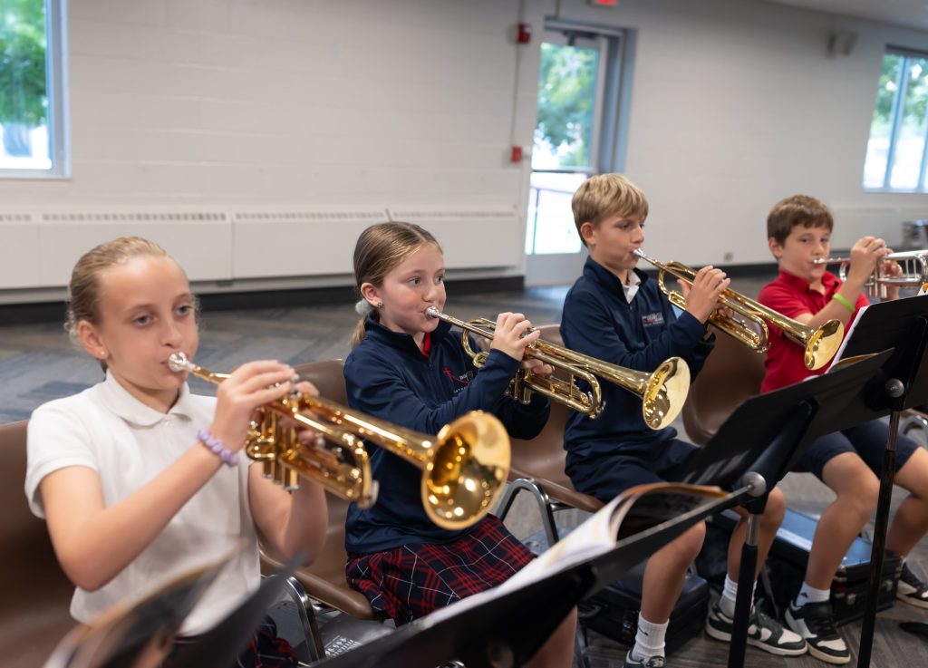 four students practice trumpets
